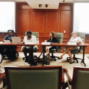 Panelists of the Olmstead at 20 event sit at a table in the front of the conference room